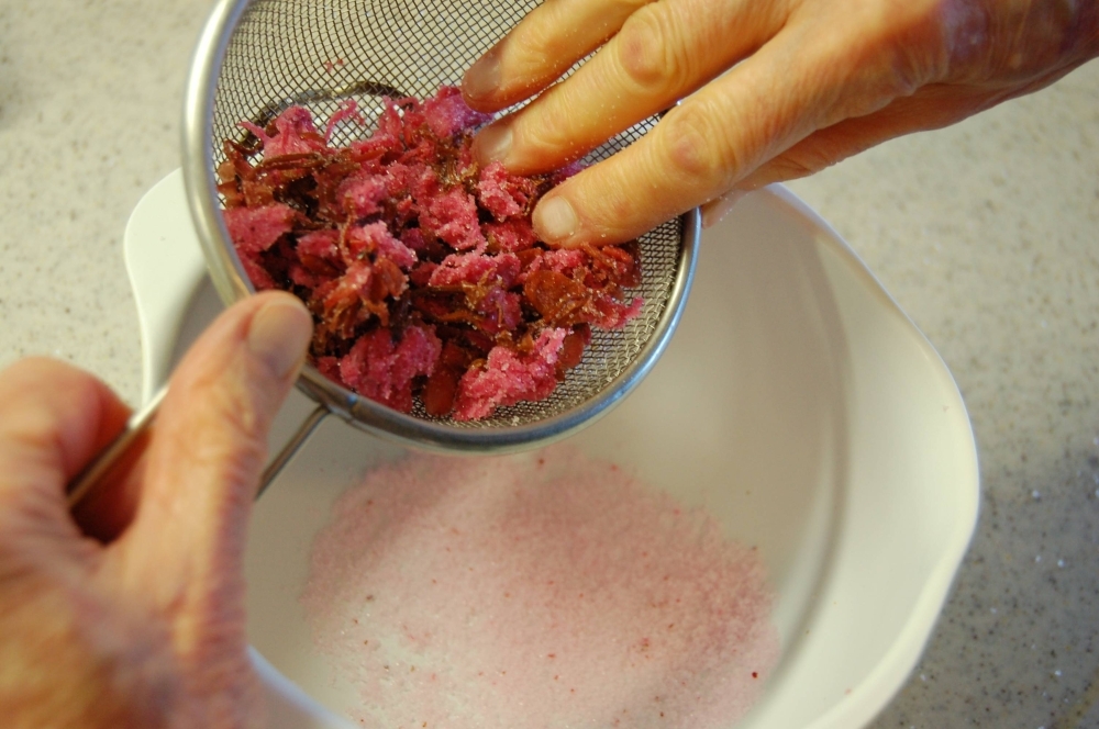 Gently shake, press, and rub the cherry blossoms against the sides of the strainer to remove as much excess salt as possible.