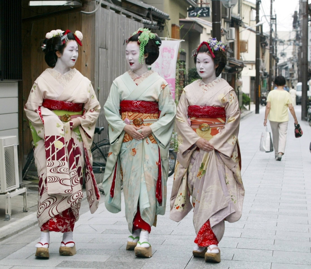 Tourists wearing rented 'maiko' costumes stroll down a street in Japan's ancient capital of Kyoto.