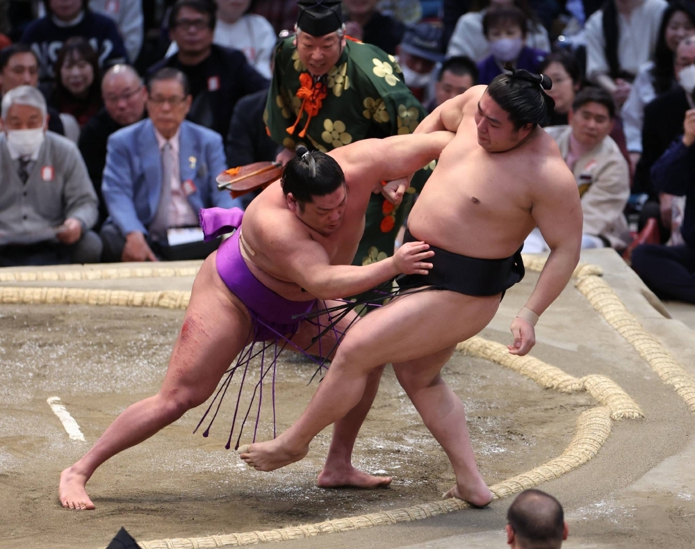 Takerufuji (left), who is making his top-division debut, shoves out Wakamotoharu to move to within a win of claiming a historic Emperor's Cup. 