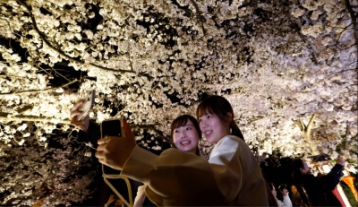 Two people try to take a selfie under the illuminated cherry blossoms in Kyoto’s Gion district last year.