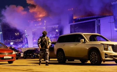 A Russian law enforcement officer walks near the burning Crocus City Hall concert venue following a shooting incident, outside Moscow, on Friday.