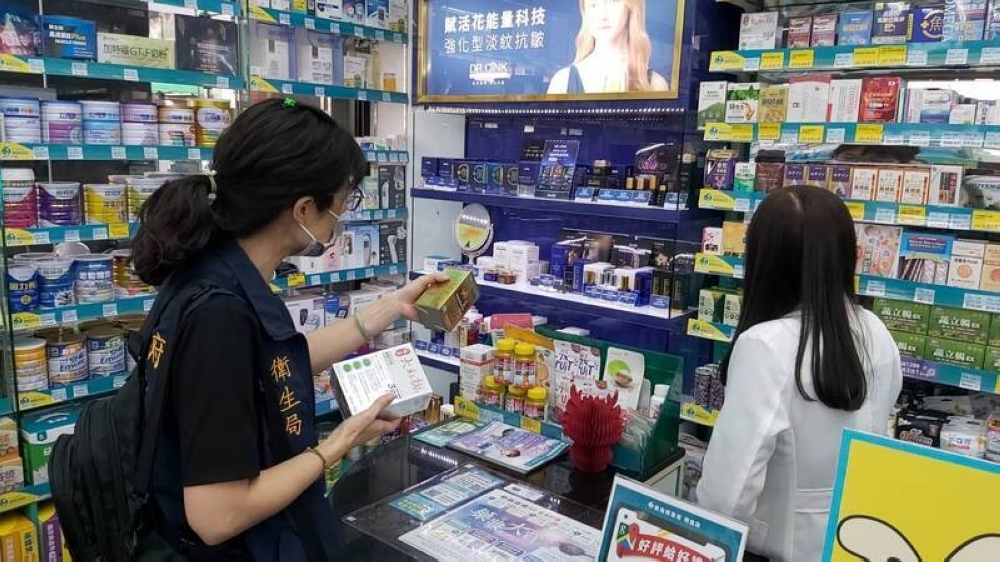 An official from the city government's health department in Kahosiung, Taiwan, checks the shelves at a drugstore in the city on Wednesday regarding Kobayashi Pharmaceutical's products.