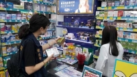 An official from the city government's health department in Kahosiung, Taiwan, checks the shelves at a drugstore in the city on Wednesday regarding Kobayashi Pharmaceutical's products. | Kahosiung City Government's Health Department / The Central News Agency / via Kyodo