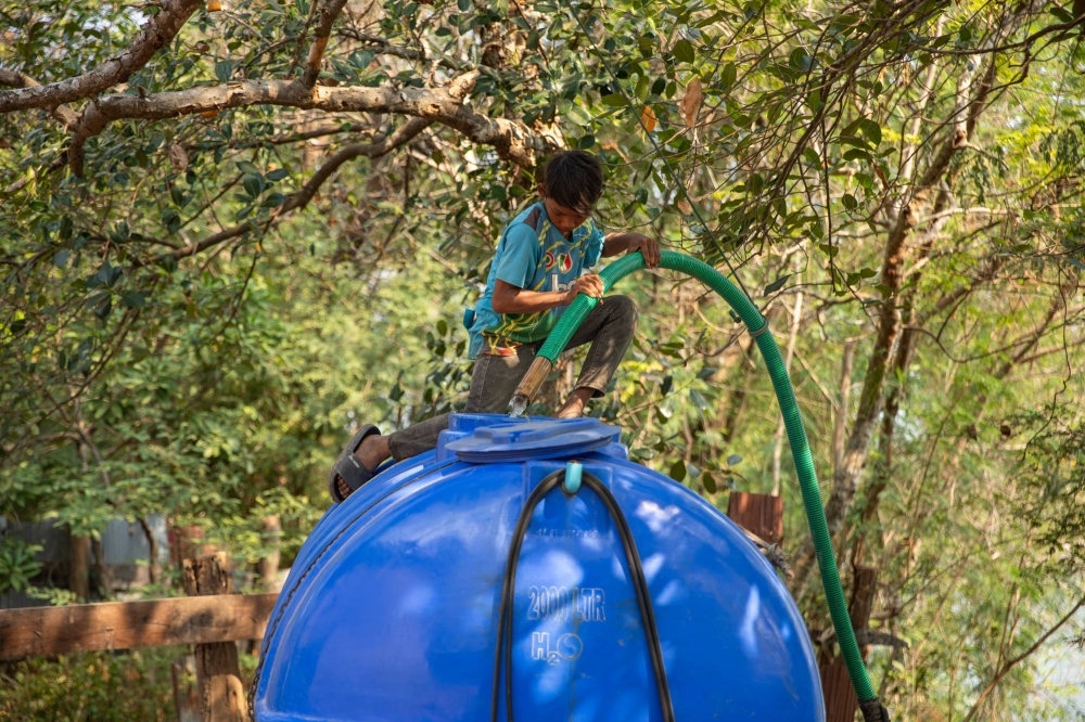 Eleven-year-old In Kao sits atop the 2,000-liter tank he is filling with unfiltered water from the Mekong River, which he will personally deliver to homes around Inn Chey in Cambodia’s Kratie Province.