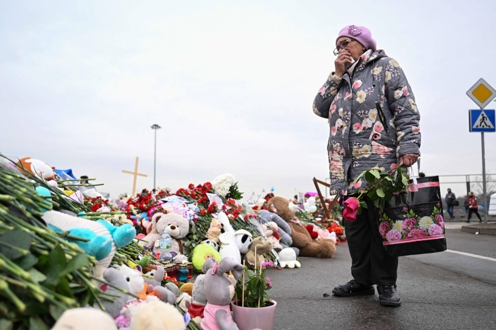 A woman pays her respects at a makeshift memorial in front of the Crocus City Hall in Moscow on Friday, a week after a deadly attack by gunmen there killed at least 143 people.