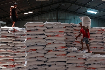 A worker stands on a pile of rice sacks as the other worker carries a sack of rice at the warehouse in Jakarta on Feb.13. Dry weather fueled by El Nino has led to a rice shortage and sent prices to record highs.