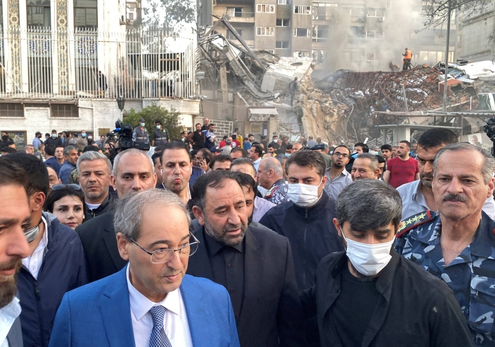 Syrian Foreign Minister Faisal Mekdad (left) walks near a damaged site after what the Iranian media said was an Israeli strike on a building close to the Iranian embassy in Damascus, Syria, on Monday.