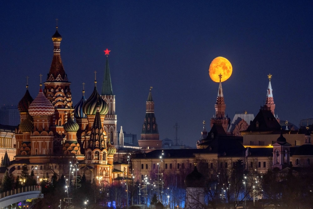 The moon rises behind the State Historical Museum, the Kremlin's towers and St. Basil's Cathedral in central Moscow on March 21. Russia has dismissed new allegations about its role in Havana syndrome as "groundless."