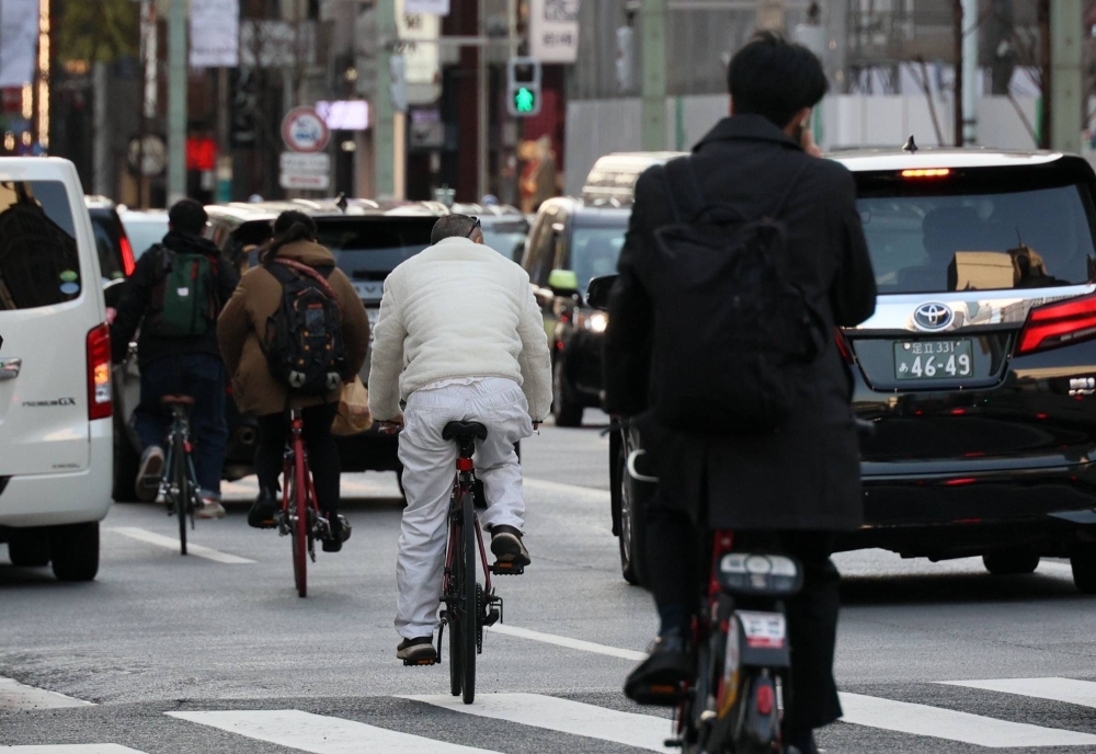 People ride bikes without wearing helmets in Tokyo in March 2023, just before a law revision over helmet wearing on April 1 that year.