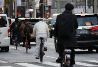 People ride bikes without wearing helmets in Tokyo in March 2023, just before a law revision over helmet wearing on April 1 that year. | Jiji
