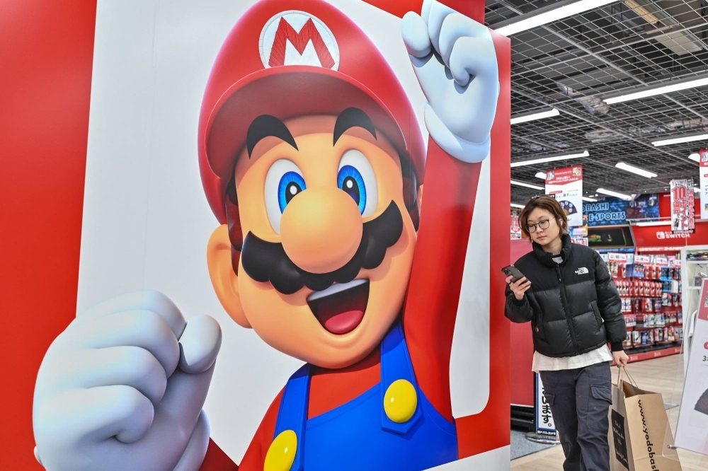 A customer walks past a display for Nintendo's Super Mario at an electronics store in Tokyo on Jan. 12. Last year, Nintendo increased salaries, in part to be competitive with other studios.