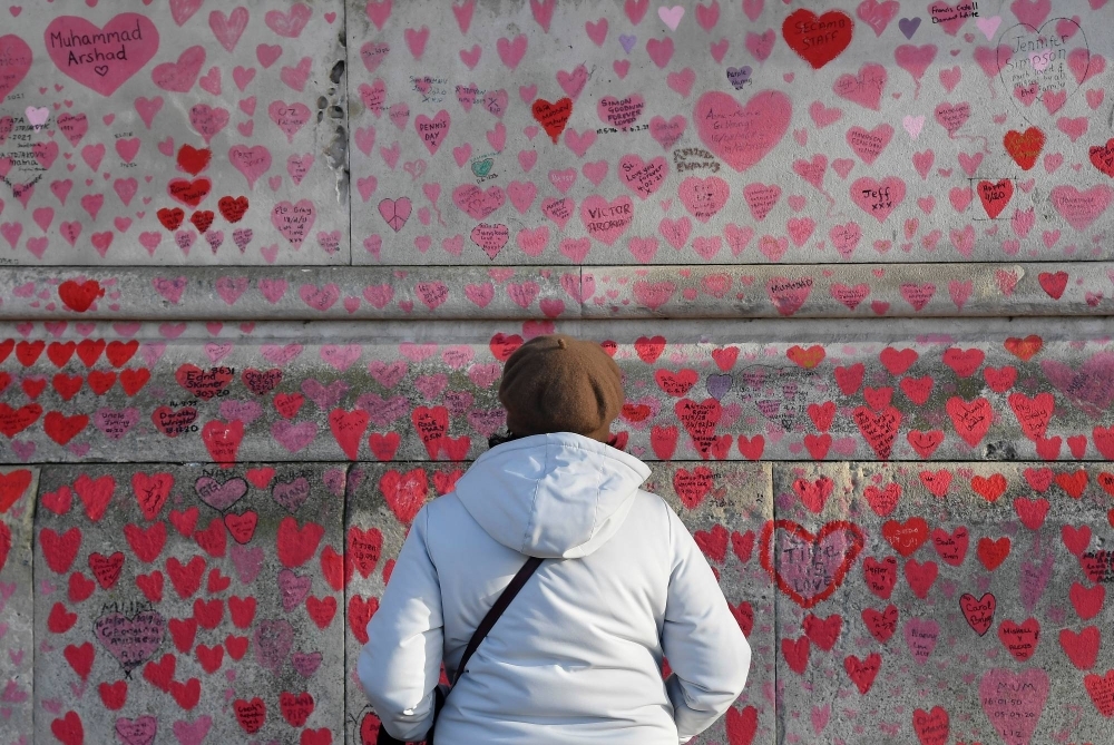 A woman views the National COVID-19 Memorial Wall, a dedication of thousands of hand-painted hearts and messages for those in the U.K. who have died from COVID-19, in London on Jan. 9, 2022.