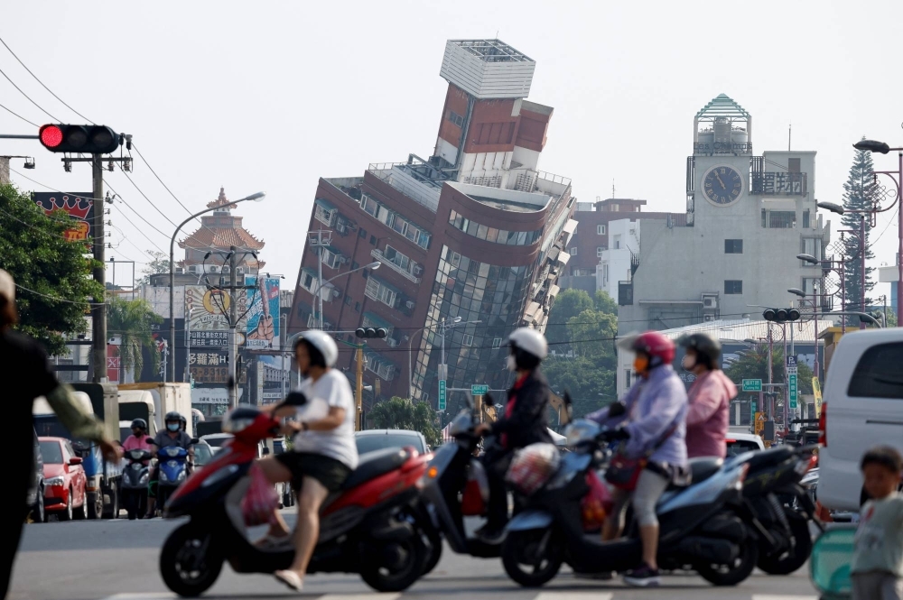 People ride motorcycles near the site where a building collapsed, following the earthquake, in Hualien, Taiwan, on Thursday.