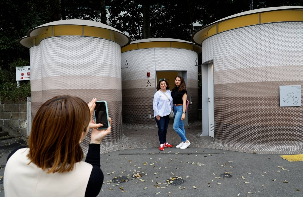 Foreign tourists get their photos taken in front of a public toilet that was redesigned as part of a project to transform public toilets into restrooms that can be used comfortably by everyone, during a Tokyo Toilet Shuttle Tour, in Shibuya Ward, on Thursday.
