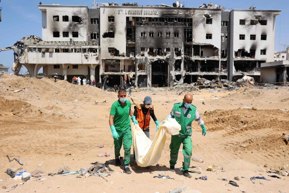 Palestinian forensic and civil defense workers recover human remains at the grounds of Shifa hospital, Gaza's largest hospital, which was reduced to rubble by a two-week Israeli raid, on Monday.
