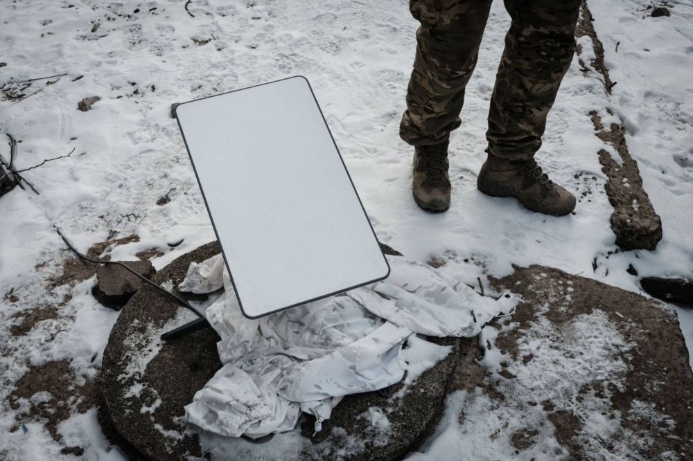 A Ukrainian serviceman stands next to a Starlink antenna near Bakhmut, Ukraine. 