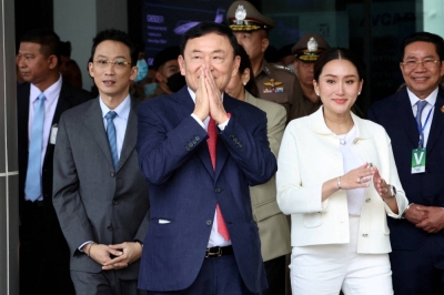Former Thai Prime Minister Thaksin Shinawatra gestures while flanked by his son Panthongtae Shinawatra and daughter Paetongtarn Shinawatra at Don Mueang airport in Bangkok in August 2023.