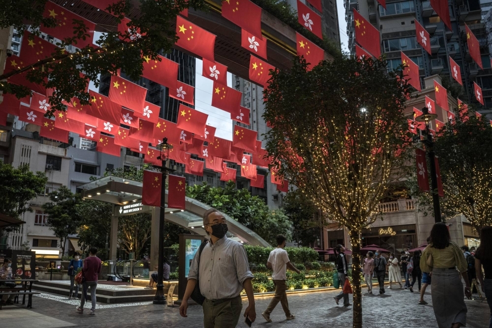 People walk under flags of China and the Hong Kong Special Administrative Region on Queen’s Road in Hong Kong in June 2022.