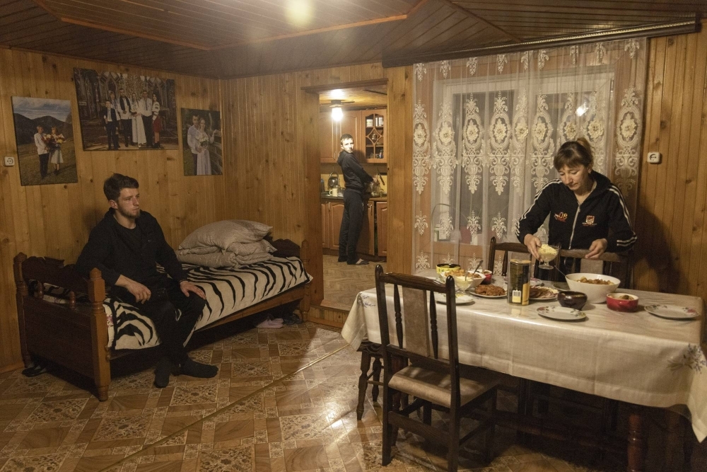 Vasyl Vanzhurak, 24, sits in his home in the town of Verkhovyna, Ukraine, as his mother and younger brother help prepare dinner on March 22. Ukraine President Volodymyr Zelenskyy probably changed the fates of thousands of Ukrainian men when he signed a law lowering the draft age to 25 from 27 this month.  