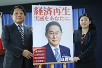 Takuya Hirai (left), chair of the Liberal Democratic Party's Public Relations Headquarters shows the party's new poster bearing a slogan created by generative artificial intelligence, at the party's headquarters on Monday. | Jiji