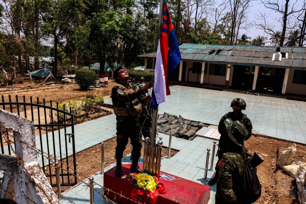 A rebel fighter of the Karen National Liberation Army (KNLA) raises Karen's national flag after burning Myanmar's national flag in Myawaddy, a Thailand-Myanmar border town, on Monday.