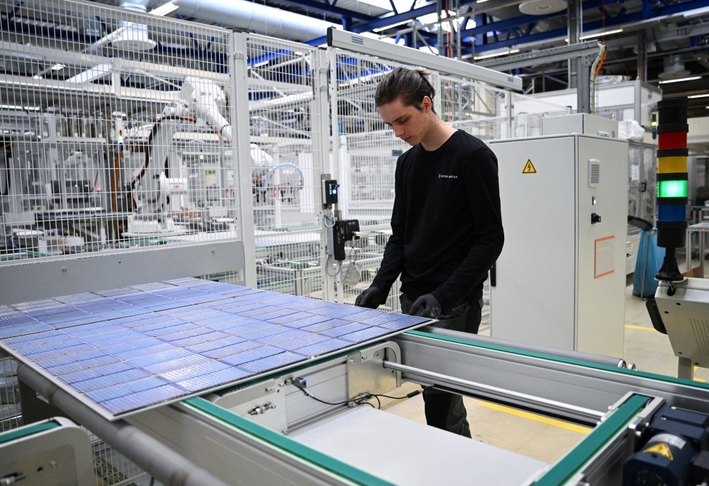 Max Lange, 19, a plant mechatronics engineering trainee from Oederan, stands next to a solar panel rolling off the assembly line as part of the last production of solar modules at the Meyer Burger Technology AG plant, due to an announced closure of the plant, in Freiberg, Germany, on March 12.