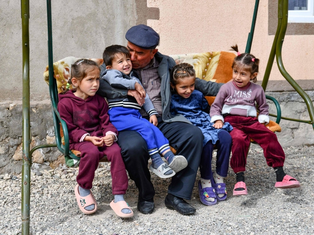 Jamoliddin Makhmaliyev sits with his grandson and granddaughters in front of his new house in the village of Khuroson, some 70 kilometers south of the Tajikistan capital Dushanbe, on March 26. “We lived in fear, until the day the mountain collapsed and destroyed our house,” recalls his wife Yodgoroy. Tajikistan is the Central Asian country most vulnerable to climate change and natural disasters.
