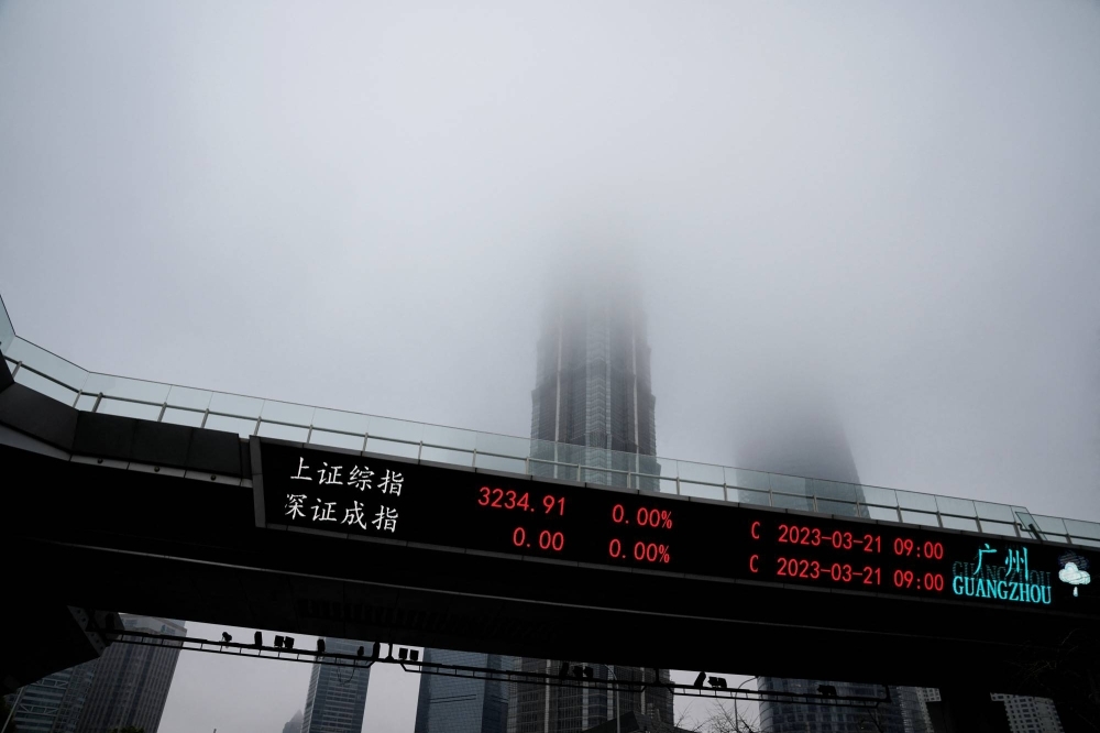 An electronic board shows stock indexes at the Lujiazui financial district in Shanghai on March 21, 2023. 