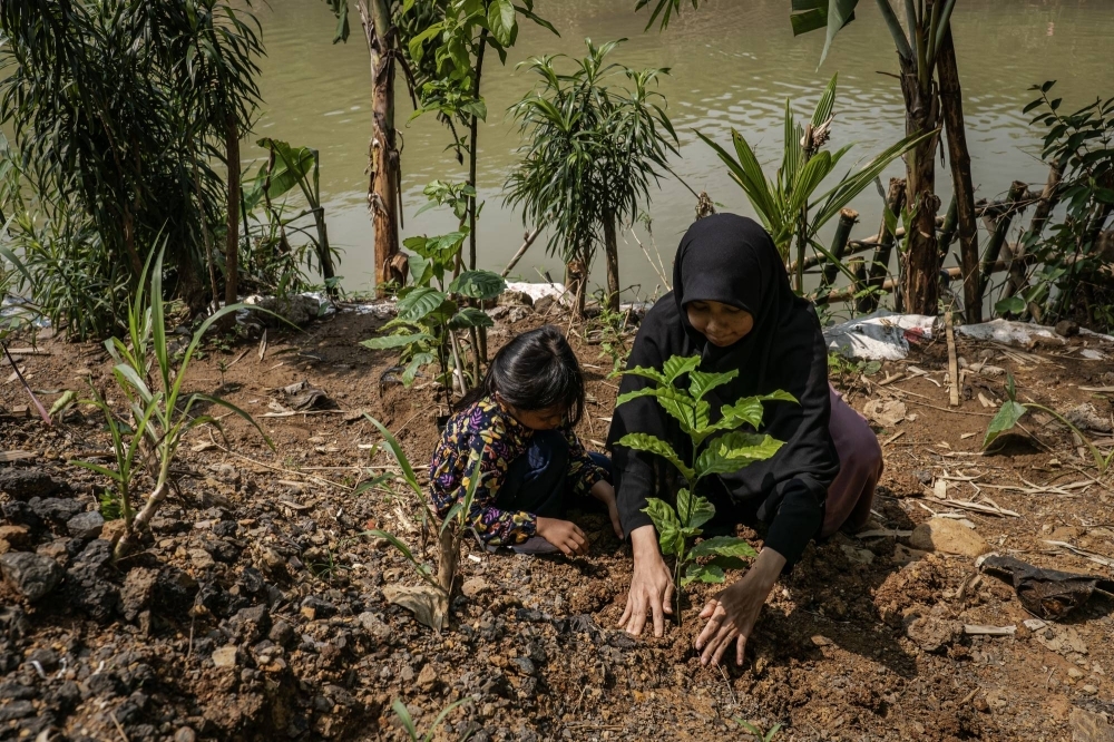 A mother and daughter plant trees on the banks of the Cikeas River in Bogor, West Java, Indonesia, in December 2023. While other Muslim nations also have strains of a “Green Islam” movement, Indonesia could be a guide for the rest of the world if it is able to transform itself.