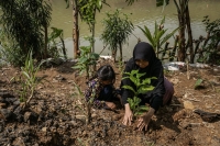 A mother and daughter plant trees on the banks of the Cikeas River in Bogor, West Java, Indonesia, in December 2023. While other Muslim nations also have strains of a “Green Islam” movement, Indonesia could be a guide for the rest of the world if it is able to transform itself. | Ulet Ifansasti / The New York Times