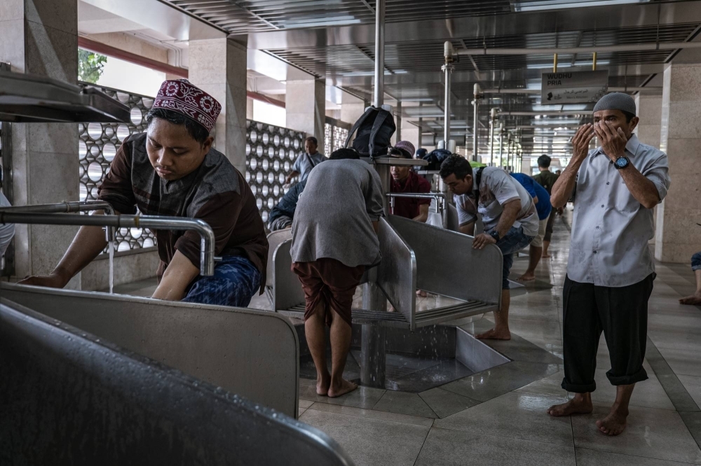 Muslim men perform ablution before Friday Prayers at the Istiqlal Mosque in Jakarta, Indonesia, in December 2023. Thanks to slow-flow faucets and a water recycling system, worshipers are using much less water to cleanse themselves before prayers.