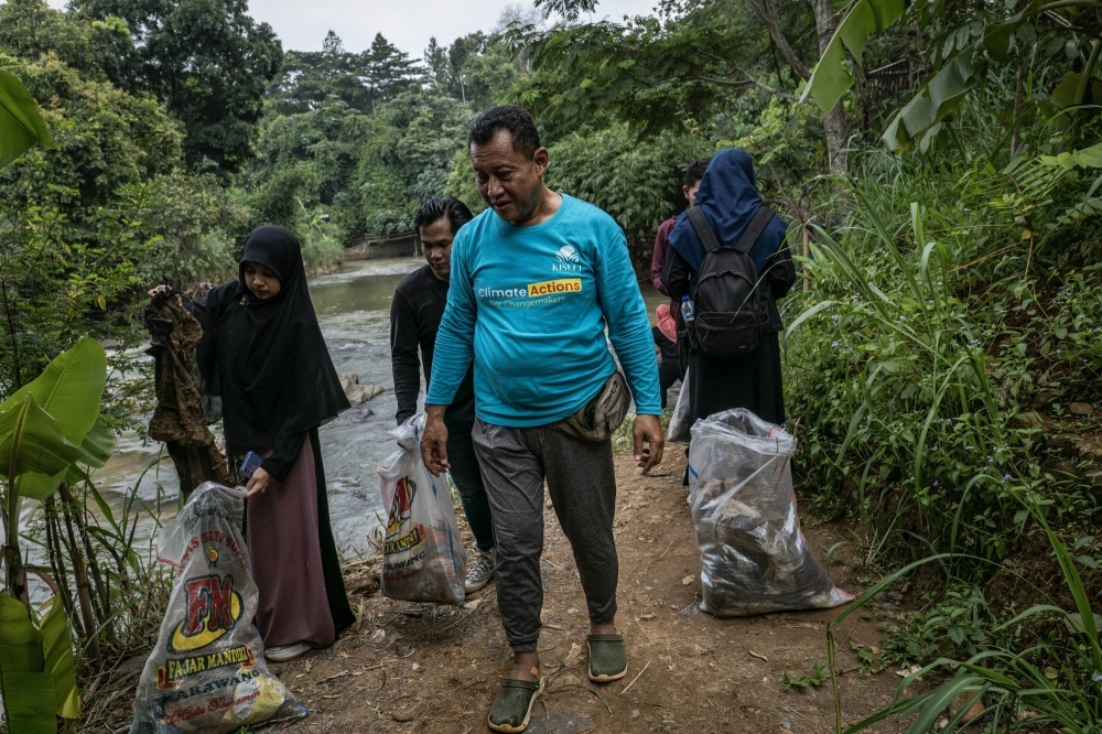 Hayu Prabowo, the head of environmental protection at the Indonesian Ulema Council, cleans up the banks of the Cikeas River with community members in Bogor, West Java, Indonesia, in December 2023. Prabowo said people “listen to religious leaders because their religious leaders say 'You can escape worldly laws, but you cannot escape God’s laws.'”