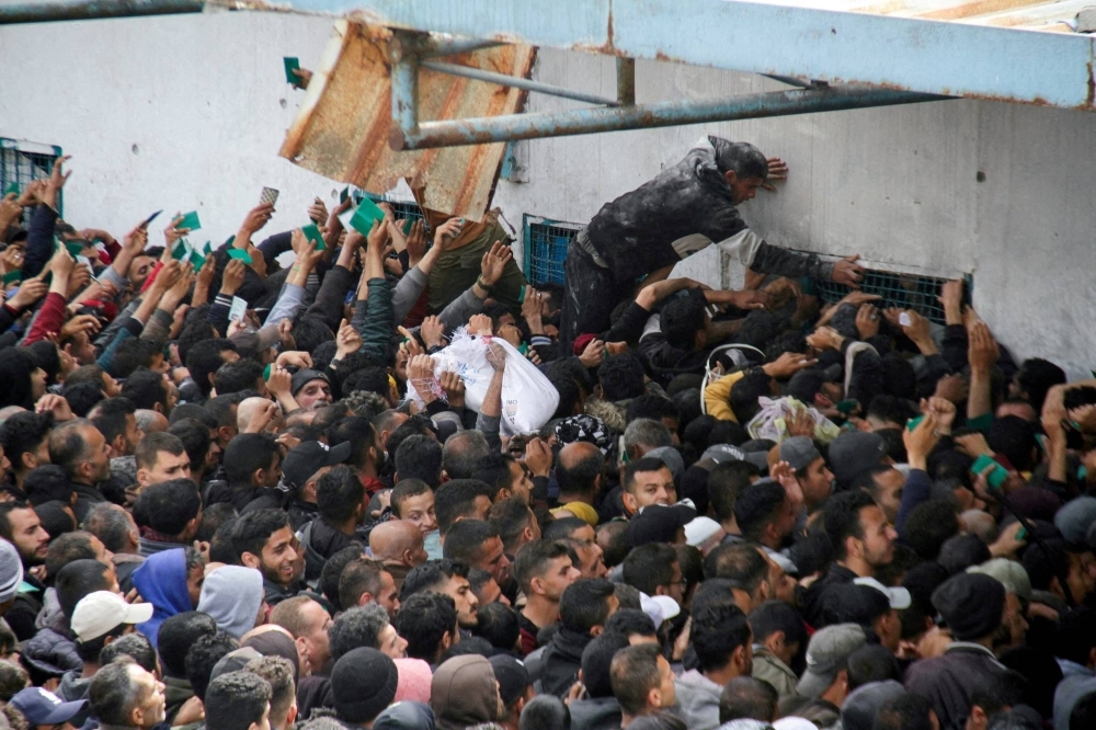 Palestinians gather to receive aid outside a UNRWA warehouse on March 18 as Gaza residents face crisis levels of hunger.