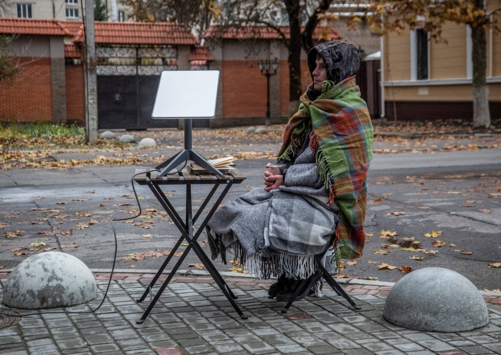 A volunteer sits near a Starlink terminal constructed for local residents at a street in Kherson, Ukraine, in November 2022.