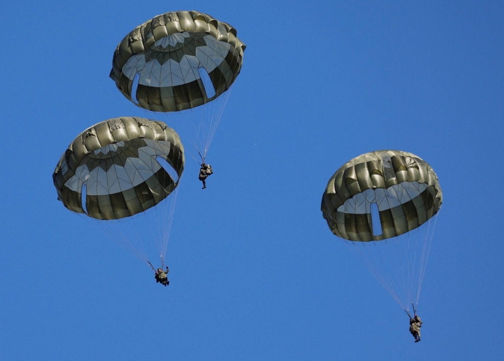 Troops from the Ground Self-Defense Force parachute from an aircraft during a joint military drill involving personnel from Japan, the U.S., Britain and Australia at the Narashino exercise field in Funabashi, Chiba Prefecture, in January 2023.