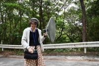 Cassondra George, a research assistant in the Environmental Science and Informatics Section at the Okinawa Institute of Science and Technology, listens to a recording of a bird call captured using a parabolic microphone in Onna, Okinawa Prefecture, on April 4. Parabolic microphones are sometimes used to identify specific bird calls. | Chris Russell
