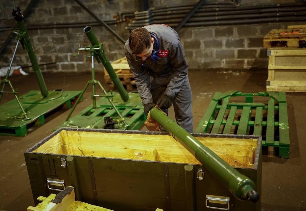 An employee prepares to place a mortar into a box at an arms production facility in an undisclosed location in Ukraine.