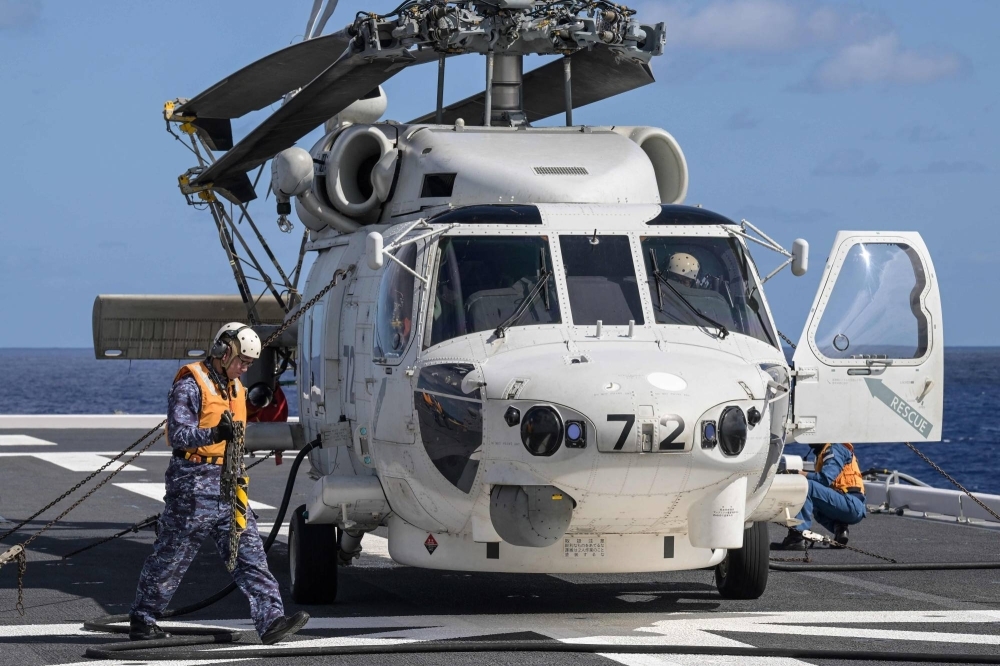 A crew member walks past an SH-60K helicopter on the deck of the Maritime Self-Defense Force's Hyuga-class Ise helicopter carrier during a joint exercise between the U.S. and Japan in the Philippine Sea on Jan. 31.