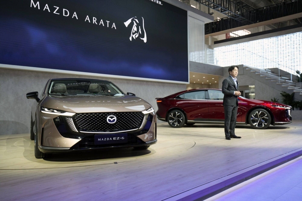 Masahiro Moro, CEO of Mazda Motor, speaks next to EZ-6 electric vehicles during the Beijing Auto Show in Beijing on Thursday.