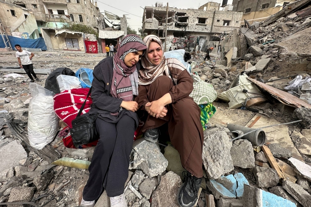 Palestinian women in Gaza sit amid the rubble of a residential building they once lived in, which was destroyed by an Israeli raid earlier this month.