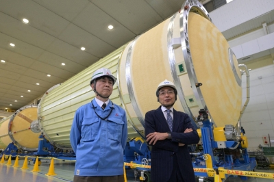 Masashi Okada (right), project manager of the H3 rocket for the Japan Aerospace Exploration Agency, and Mayuki Niitsu, Mitsubishi Heavy industries' H3 rocket project manager, in front of a rocket core at a Mitsubishi plant in Tobishima, Aichi Prefecture, on March 21
