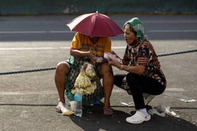 Vendors wearing headwear for protection against the sun talk amid the heat in Manila on Friday.