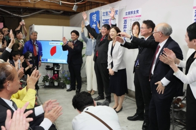 The Constitutional Democratic Party of Japan's Natsumi Sakai (center) celebrates with other CDP officials and supporters on Sunday in Tokyo's Koto Ward after being announced as the winner of the Tokyo No. 15 district by-election.