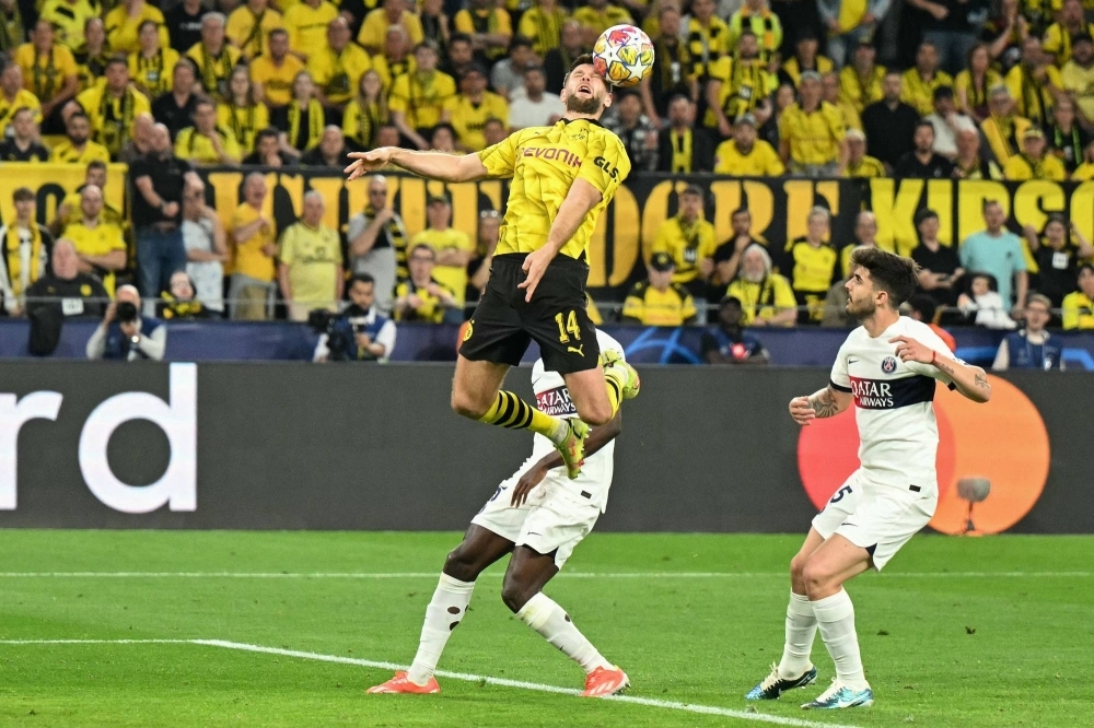 Dortmund's Niclas Fuellkrug jumps to head the ball in front of Paris St. Germain's Lucas Beraldo (right) and Ousmane Dembele during the first leg of their Champions League semifinal in Dortmund, Germany, on Wednesday.