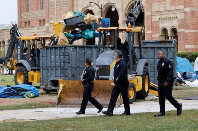 Police walk past people operating bulldozers to remove the remnants of a protest encampment in support of Palestinians that police broke down the previous night on the campus of the University of California Los Angeles on Thursday.
