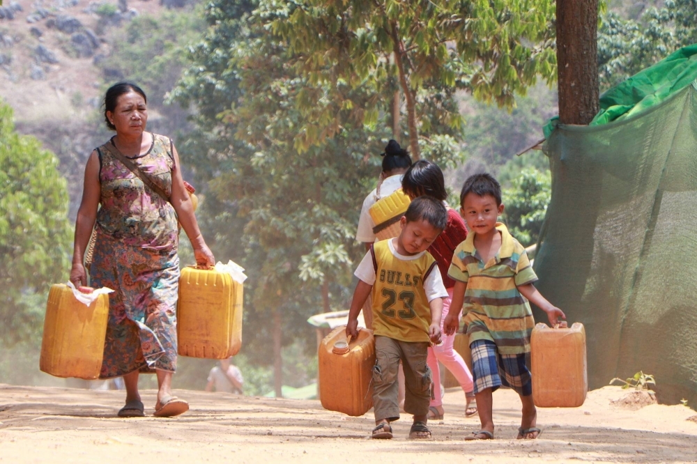 A Kayah woman and children carrying containers from a delivery of drinking water in Myanmar's eastern Kayah state.