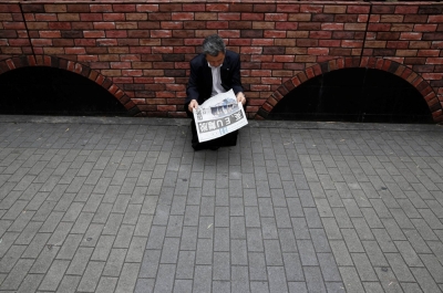 A businessman reads a newspaper outside a train station in Tokyo.