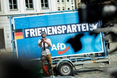 A man films with a smartphone in front a placard for the German far-right Alternative for Germany (AfD) party during a campaign event for the upcoming European Parliament elections, and ahead of Saxony's municipal and state elections, in Dresden, eastern Germany, on May 1.
