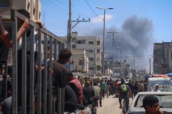 Palestinians crowd a street as smoke billows after Israeli strikes in Rafah on Tuesday.