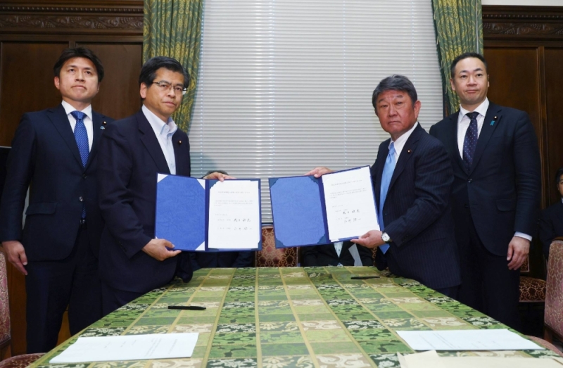 Liberal Democratic Party Secretary-General Toshimitsu Motegi (second from right) and his Komeito counterpart Keiichi Ishii (second from left) hold a signed agreement on political funding reform, on Thursday in the Diet.
